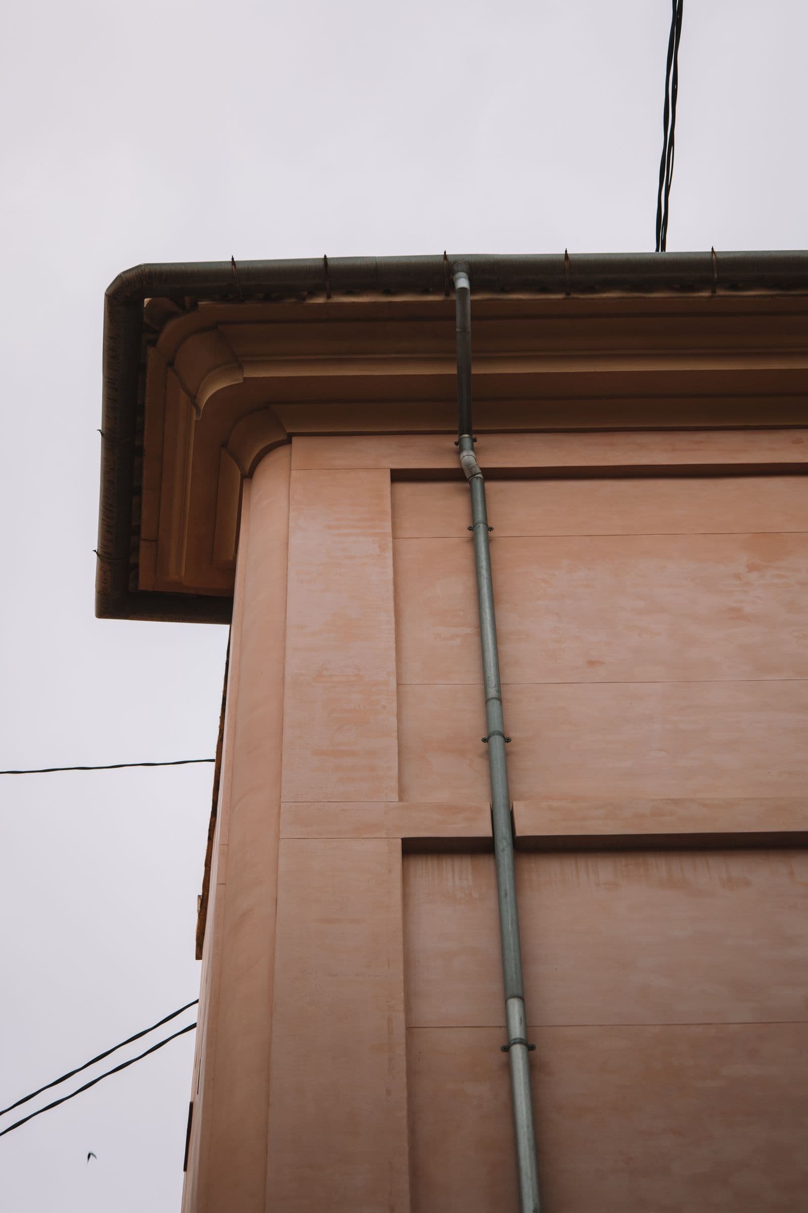 Metal gutter and downpipe on a building corner below the roofline